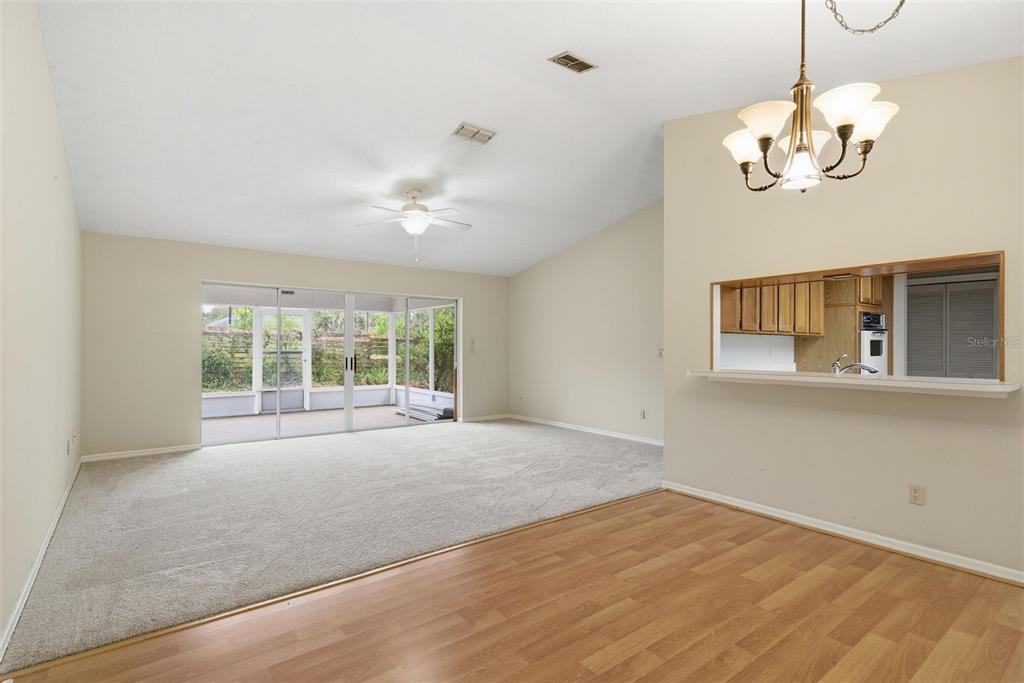 A living room with beige carpet and a sliding glass door leading to a screened porch — 6068 W DOUNERAY LOOP, CRYSTAL RIVER, FL