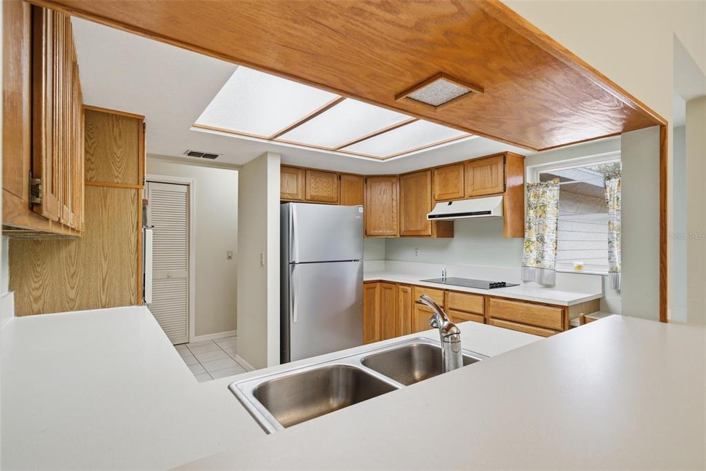 A kitchen features oak cabinets, white countertops, a stainless steel refrigerator, and a skylight — 6068 W DOUNERAY LOOP, CRYSTAL RIVER, FL