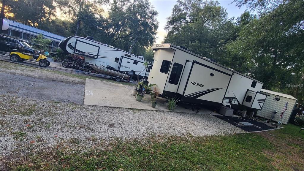 An exterior view shows two large recreational vehicles parked on a concrete pad and gravel — 25205 NE 142ND STREET, SALT SPRINGS, FL