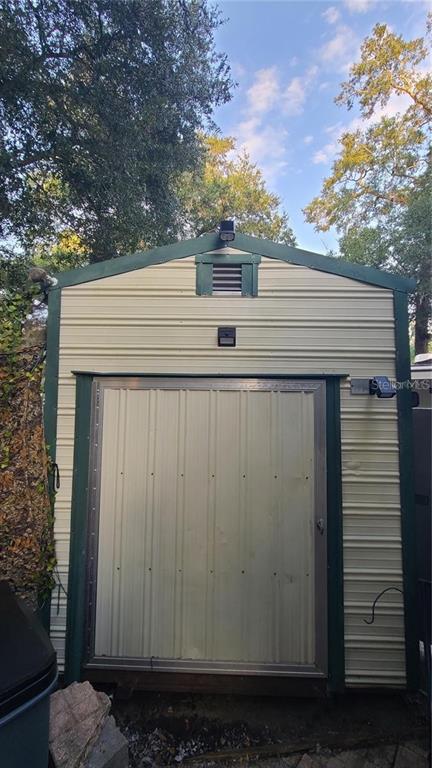 A metal storage shed with a single door, green trim, and exterior lighting — 25205 NE 142ND STREET, SALT SPRINGS, FL