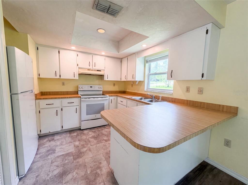 A kitchen with white cabinets, wood-look laminate countertops, white appliances, and light-colored walls — 3664 SW IVY PLACE, DUNNELLON, FL