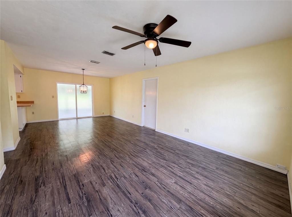 A spacious room with light yellow walls, dark wood-look flooring, and a ceiling fan — 3664 SW IVY PLACE, DUNNELLON, FL