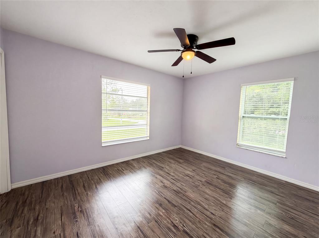 An empty bedroom features light purple walls, dark wood-look flooring, and a ceiling fan — 3664 SW IVY PLACE, DUNNELLON, FL