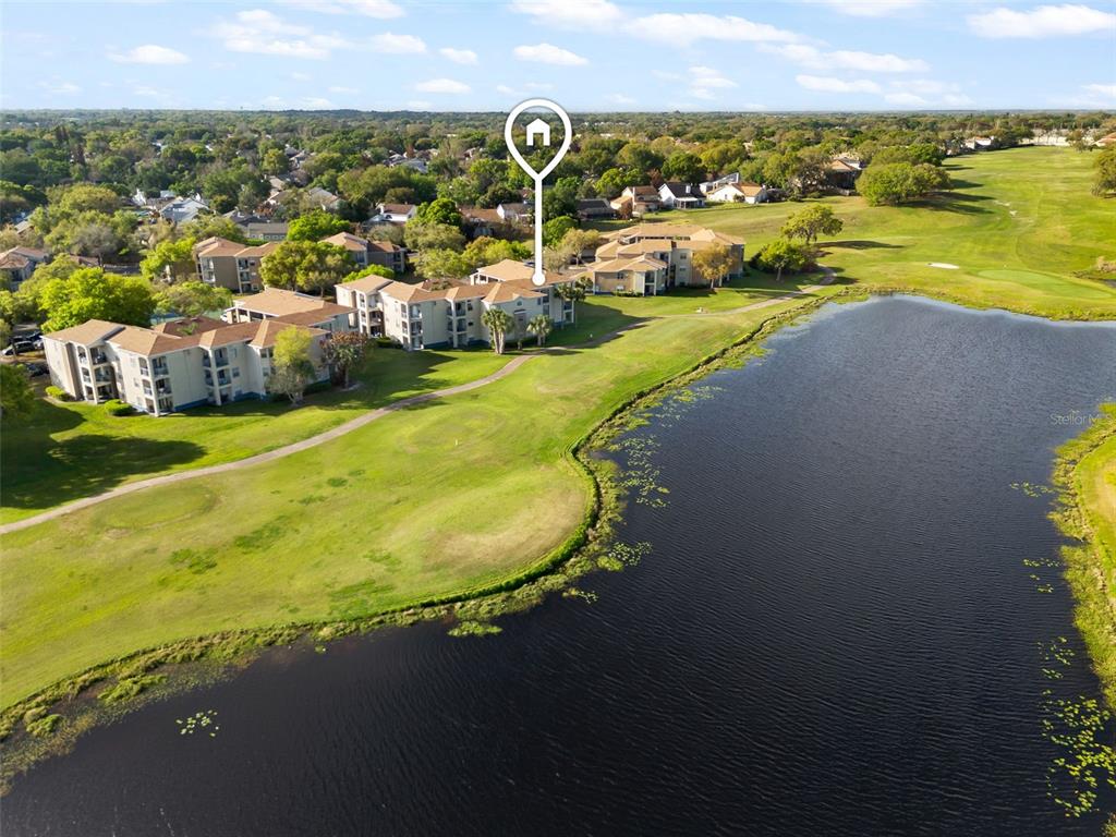 An aerial view shows apartment buildings situated next to a golf course and a lake — 7320 WESTPOINTE BOULEVARD UNIT 533, ORLANDO, FL