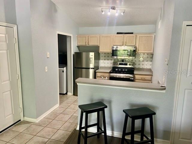 A kitchen features light wood cabinets, stainless steel appliances, and a gray countertop — 8939 LATREC AVENUE UNIT 1307, ORLANDO, FL