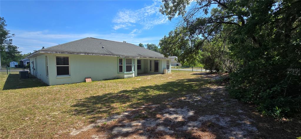 A single-story house with a light green exterior, a garage, and a wooded background — 12771 SW 58TH CIRCLE, OCALA, FL