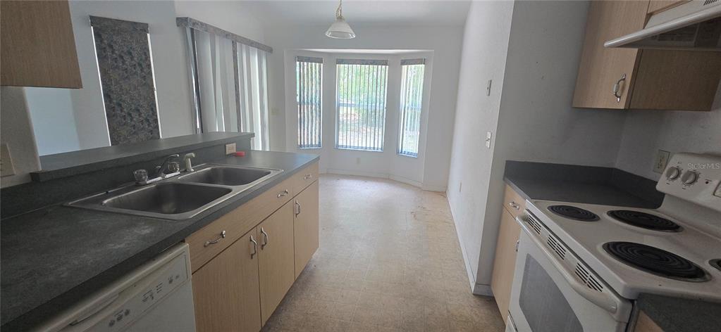 A kitchen features light wood cabinets, a white electric range, and a gray laminate countertop — 12771 SW 58TH CIRCLE, OCALA, FL