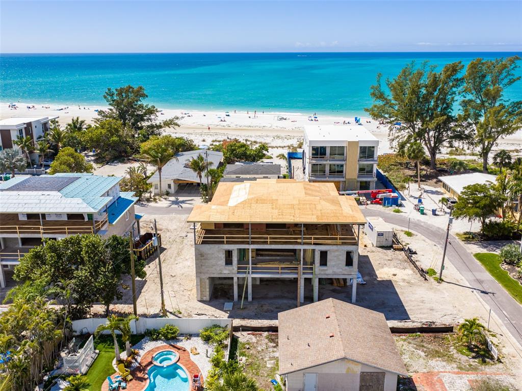 A three-story white house with a metal roof, two garages, and multiple balconies — 107 TUNA STREET, ANNA MARIA, FL