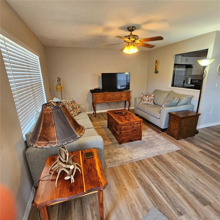 A living room features light gray sofas, a wooden coffee table, and wood-look flooring — 301 ANDOVER PLACE S UNIT 175, SUN CITY CENTER, FL