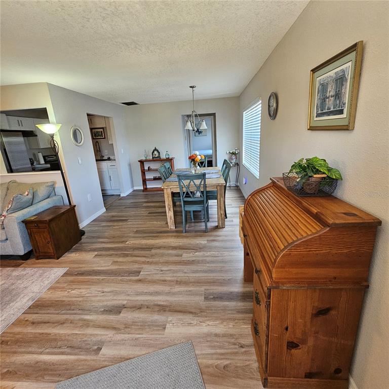 A dining area with a wooden table and chairs sits between a living room and kitchen — 301 ANDOVER PLACE S UNIT 175, SUN CITY CENTER, FL