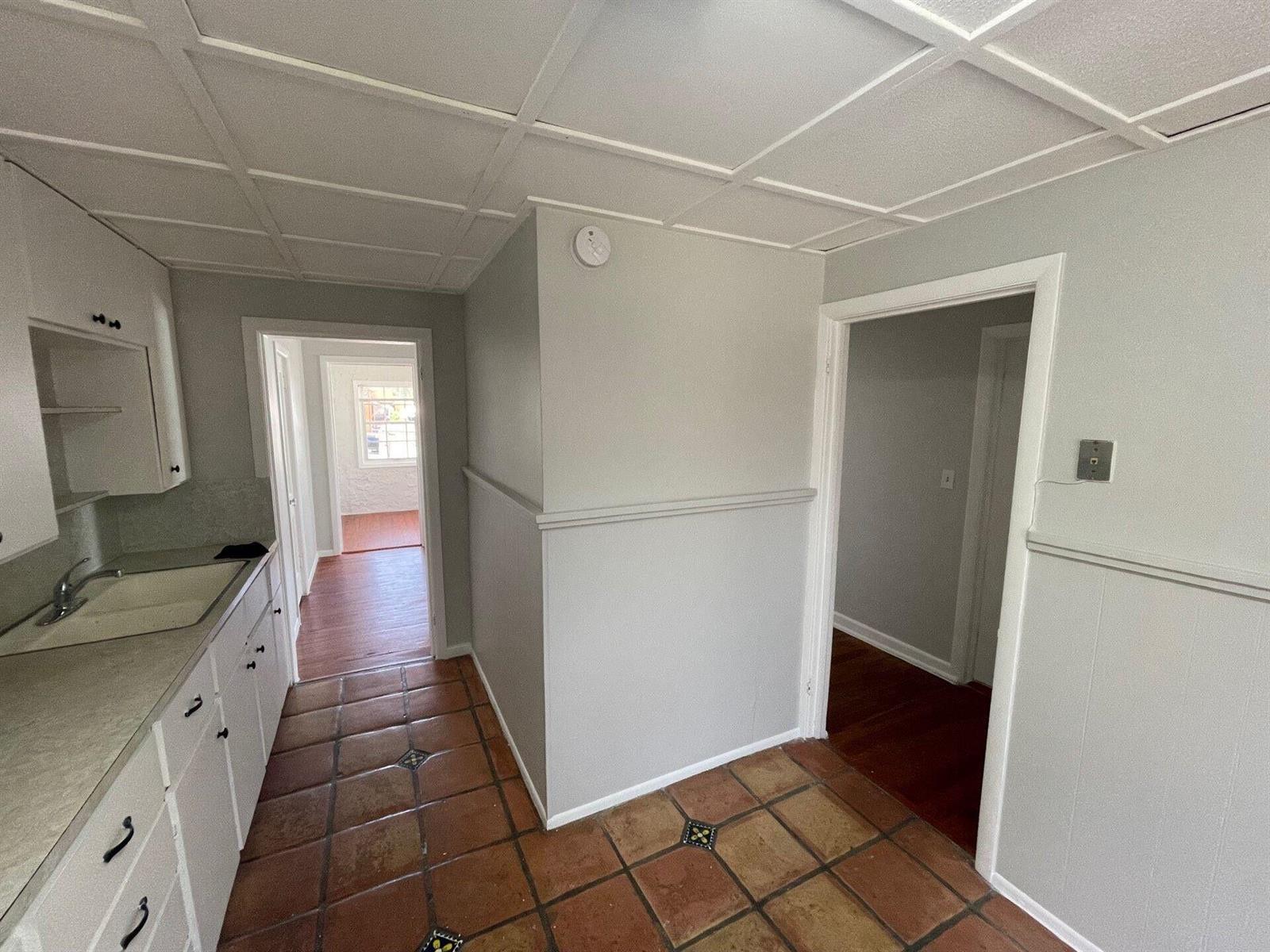 A kitchen with white cabinets, a tiled floor, and doorways leading to other rooms — 736 Omar Road # 1, West Palm Beach FL 33405, WEST PALM BEACH, FL