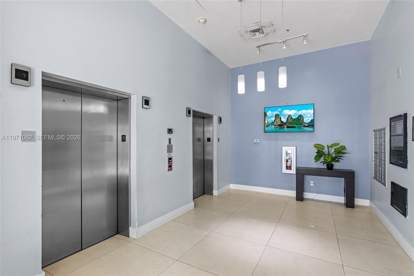 An elevator lobby features two stainless steel elevators, light blue walls, and tile flooring — 7275 SW 90th Way # 404, Miami FL 33156, MIAMI, FL