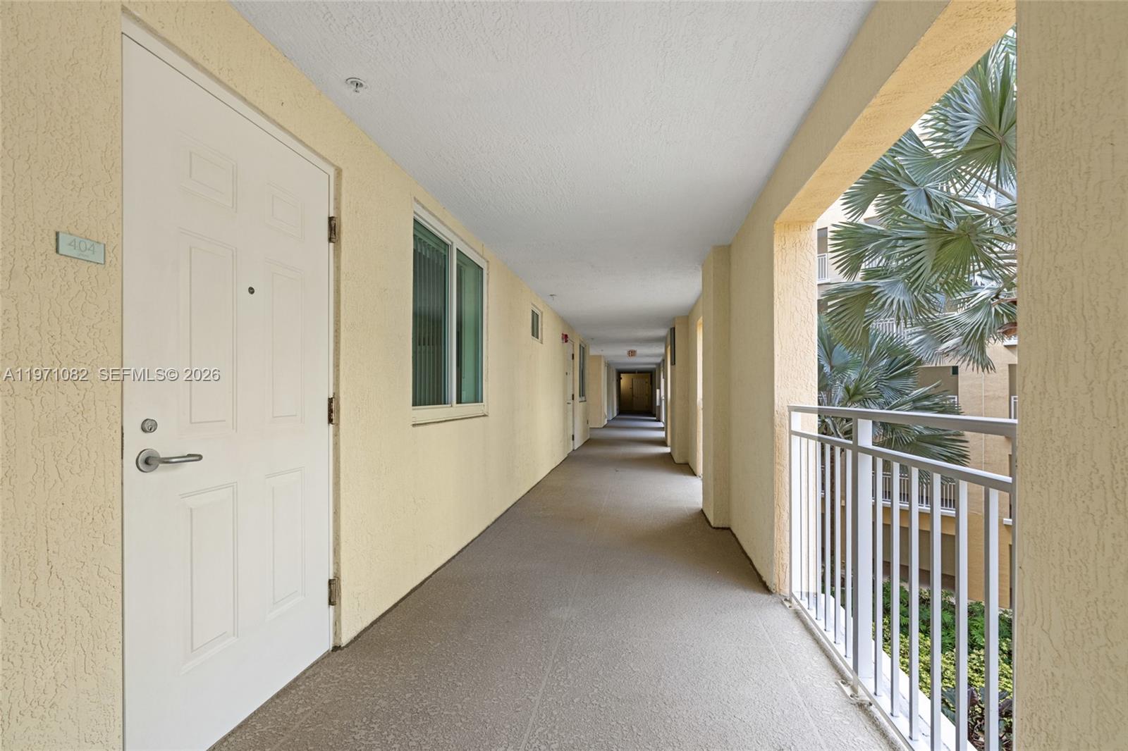 An outdoor apartment hallway features a white door, a window, and a metal railing — 7275 SW 90th Way # 404, Miami FL 33156, MIAMI, FL