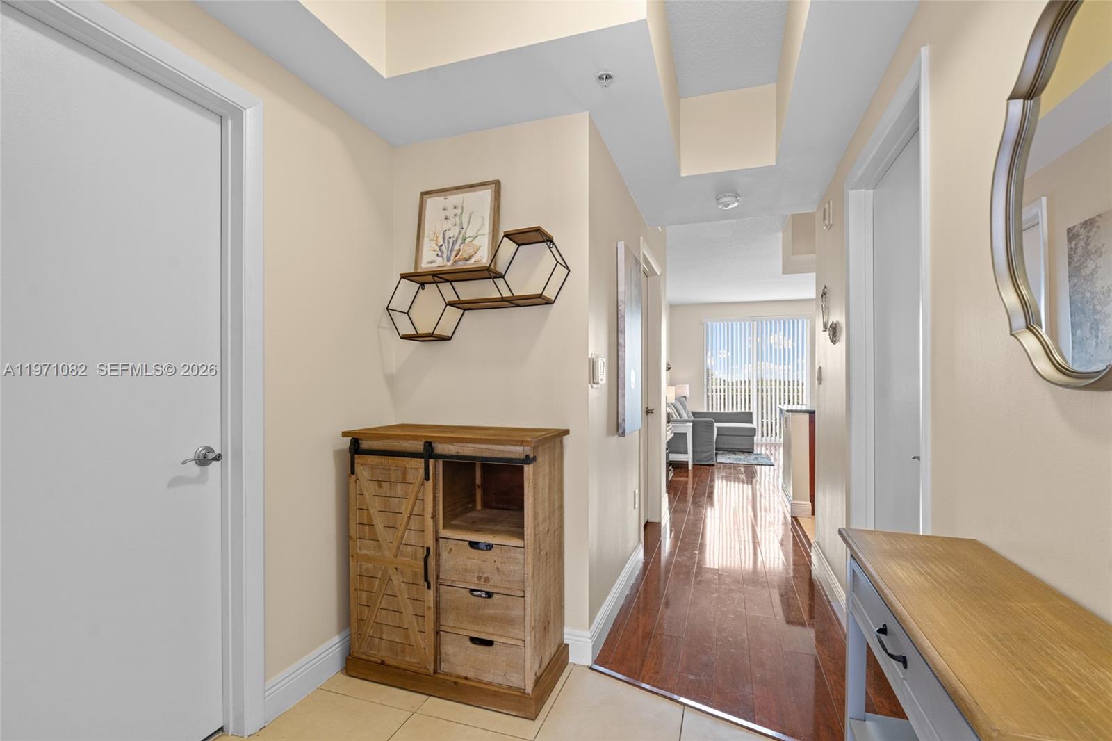 A hallway with tile flooring leads to a living area with wood floors and windows — 7275 SW 90th Way # 404, Miami FL 33156, MIAMI, FL