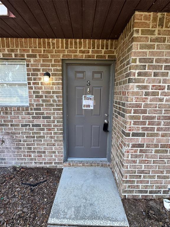 A gray front door marked with the number three is set into a brick exterior — 1197-1197 BENTLEY ROAD UNIT 3, LEESBURG, FL