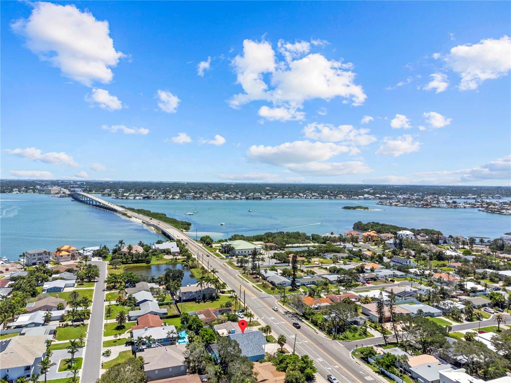 An aerial view shows a residential neighborhood near a long bridge over a body of water — 107 CAUSEWAY BOULEVARD, BELLEAIR BEACH, FL