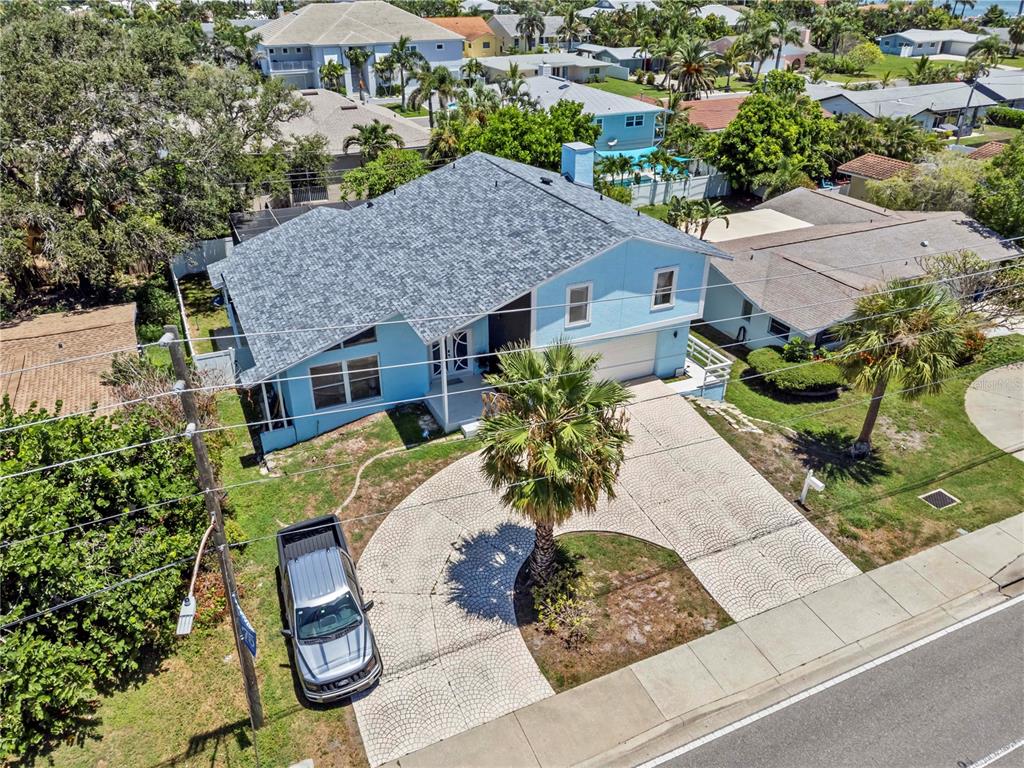 An aerial view of a light blue house with a patterned driveway and palm tree — 107 CAUSEWAY BOULEVARD, BELLEAIR BEACH, FL
