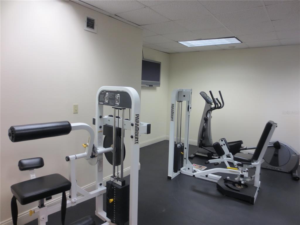 A bedroom features a stainless steel refrigerator, dark wood cabinets, a microwave, and a dresser — 7150 N TAMIAMI TRAIL UNIT C226, SARASOTA, FL
