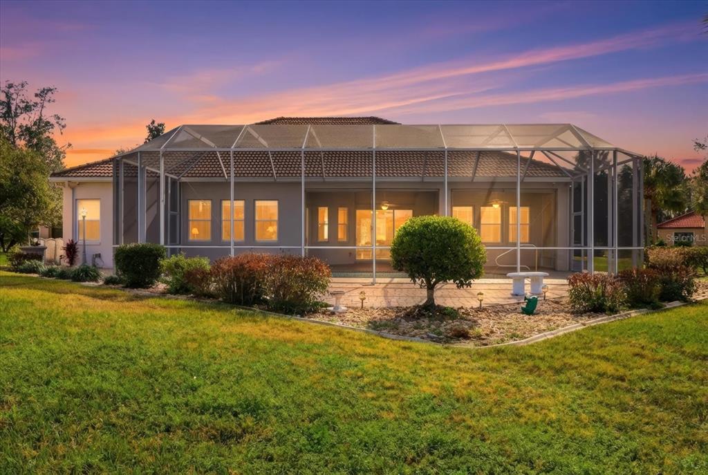 The exterior rear view of a house features a screened-in pool patio and landscaped yard — 1165 W BEAGLE RUN LOOP, HERNANDO, FL