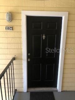 A black front door with a silver knocker is set in a yellow siding wall — 1025 S HIAWASSEE ROAD UNIT 2226, ORLANDO, FL
