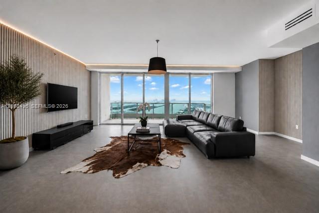 A modern living room features a black leather sectional, cowhide rug, and floor-to-ceiling windows — 900 Biscayne Blvd, Miami FL 33132, MIAMI, FL