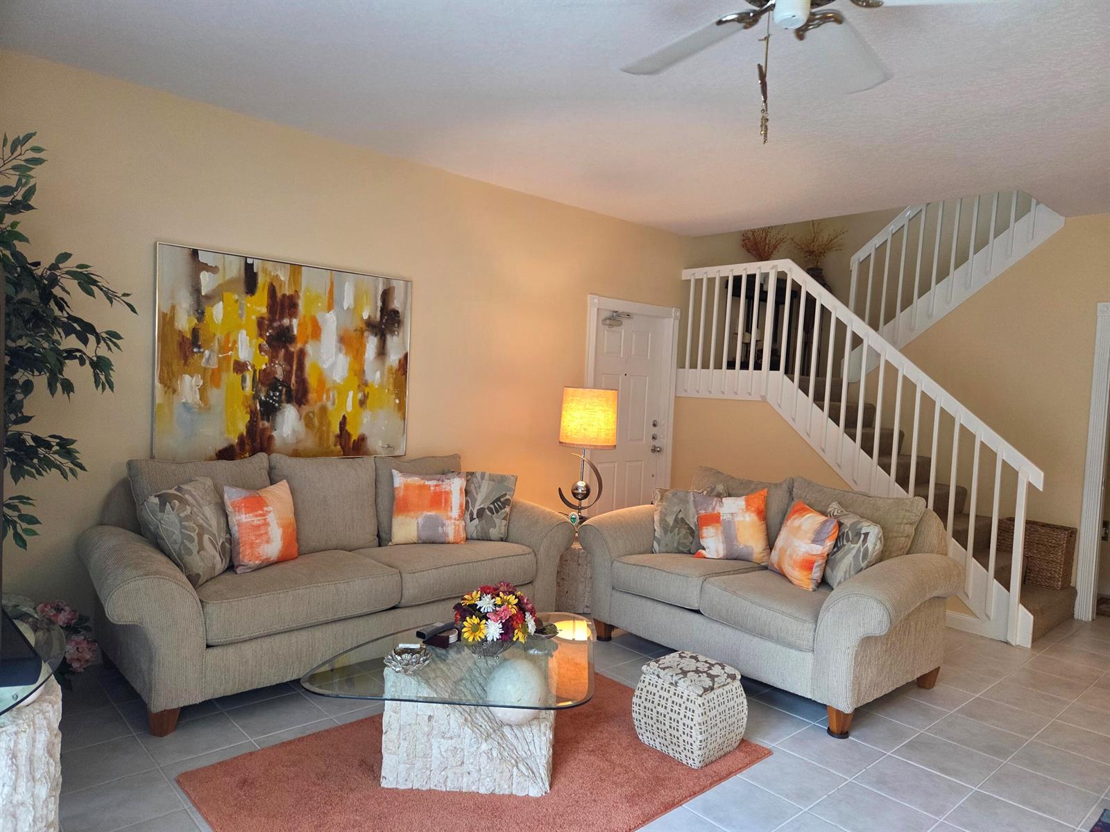 A living room features two beige sofas, a glass coffee table, and a white staircase — 58 Tall Oaks Circle, Tequesta FL 33469, TEQUESTA, FL