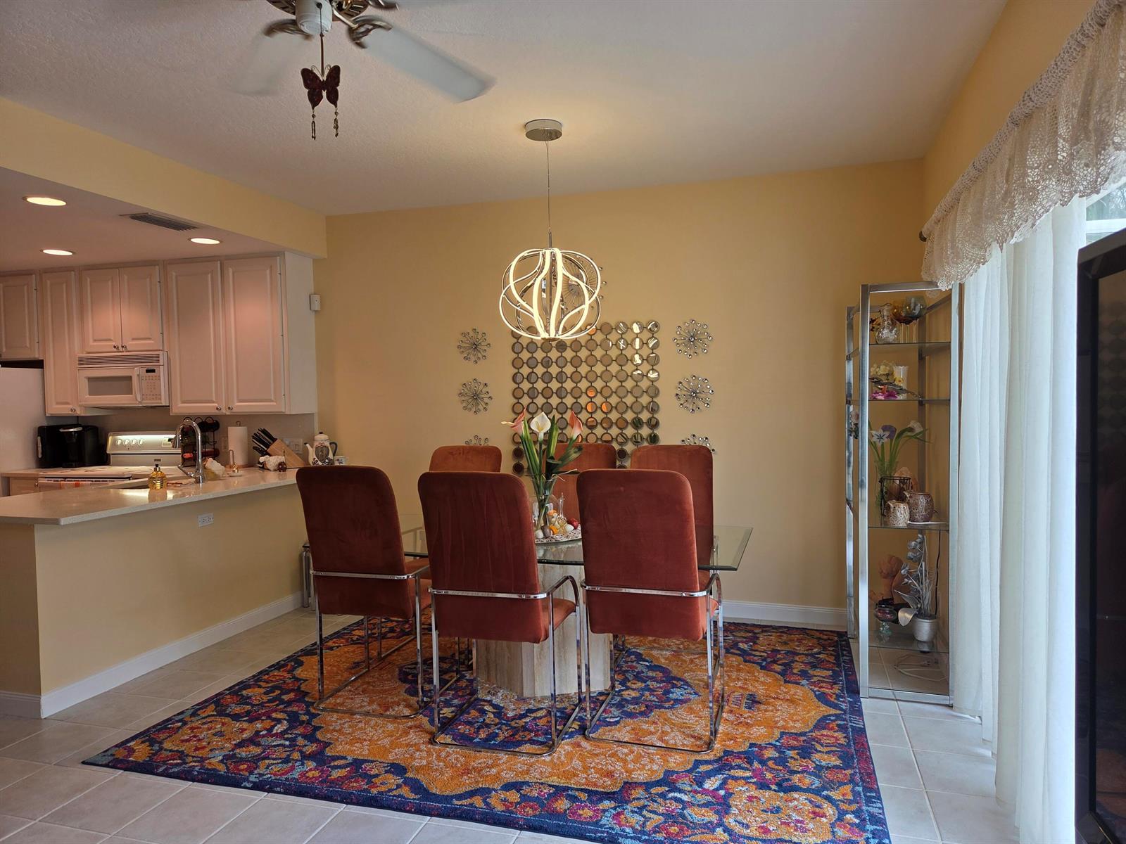 A dining room with a glass table, velvet chairs, a patterned rug, and a pendant light — 58 Tall Oaks Circle, Tequesta FL 33469, TEQUESTA, FL