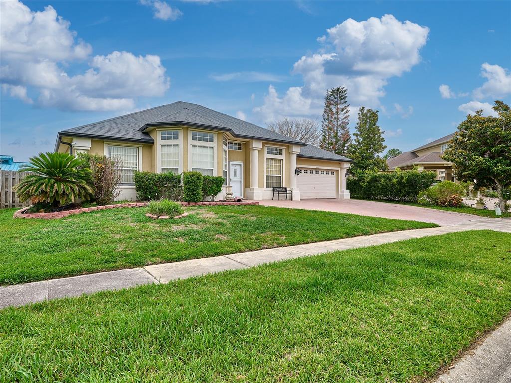 A single-story house with a tan exterior, a gray roof, and a paved driveway — 407 THUNDER GULCH COURT, ORLANDO, FL