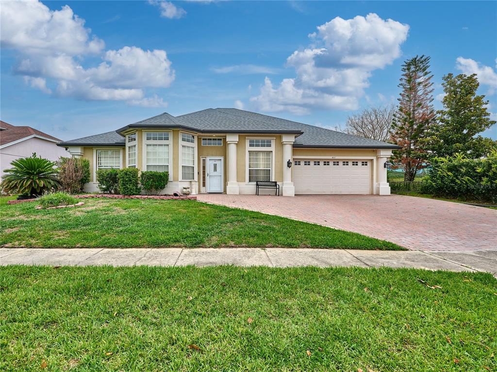 A single-story house with a beige stucco exterior, a brick driveway, and a two-car garage — 407 THUNDER GULCH COURT, ORLANDO, FL