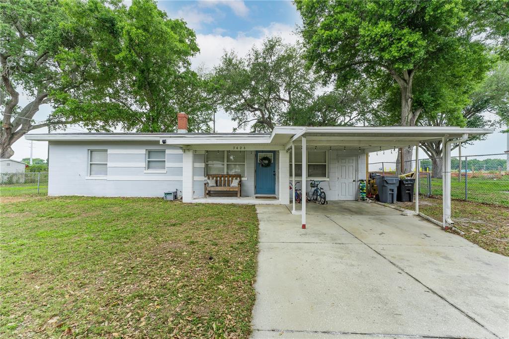 A single-story light blue house with a concrete driveway, carport, and a front porch — 3426 HICKORY STREET NW, WINTER HAVEN, FL