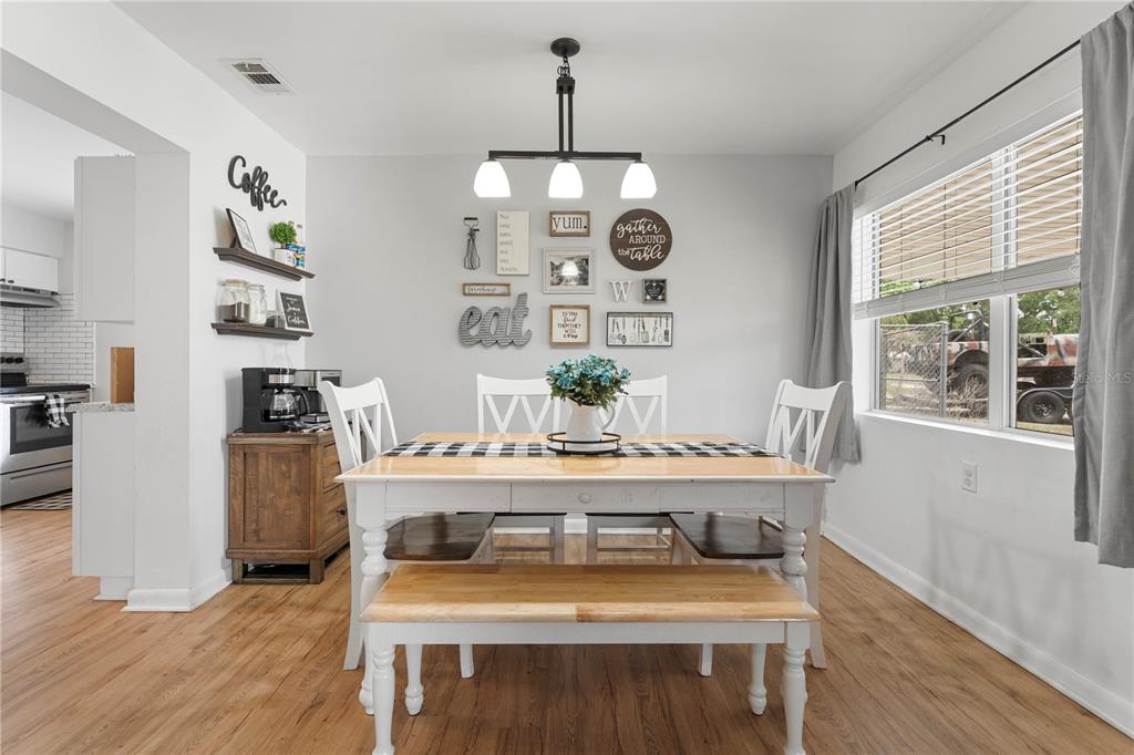 A dining room features a white table with a bench, chairs, and a gallery wall — 3426 HICKORY STREET NW, WINTER HAVEN, FL