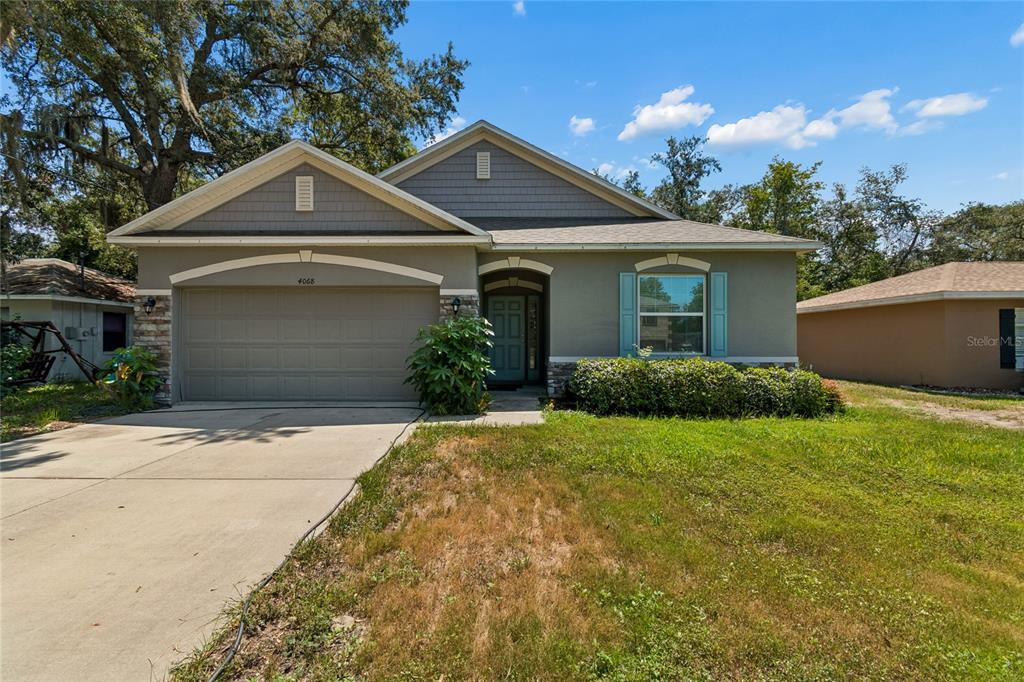 A single-story house with a two-car garage, stone accents, and a front lawn — 4068 MENDOTA AVENUE, SPRING HILL, FL