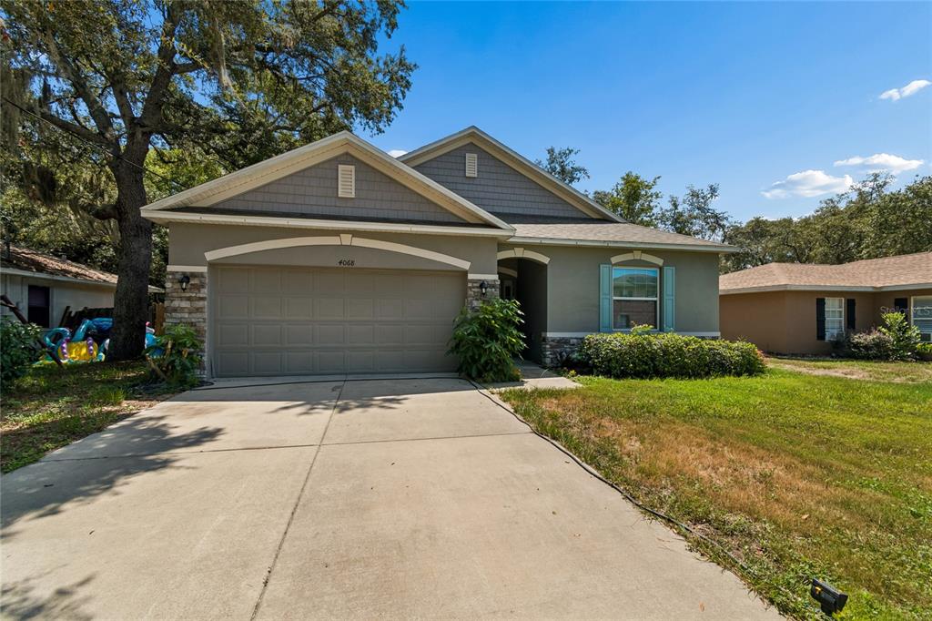 A single-story house with a two-car garage, gray siding, and a concrete driveway — 4068 MENDOTA AVENUE, SPRING HILL, FL