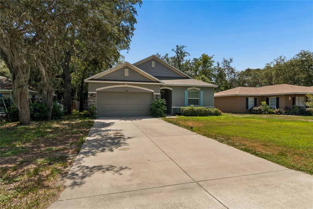 A single-story suburban house with a concrete driveway, two-car garage, and a front lawn — 4068 MENDOTA AVENUE, SPRING HILL, FL