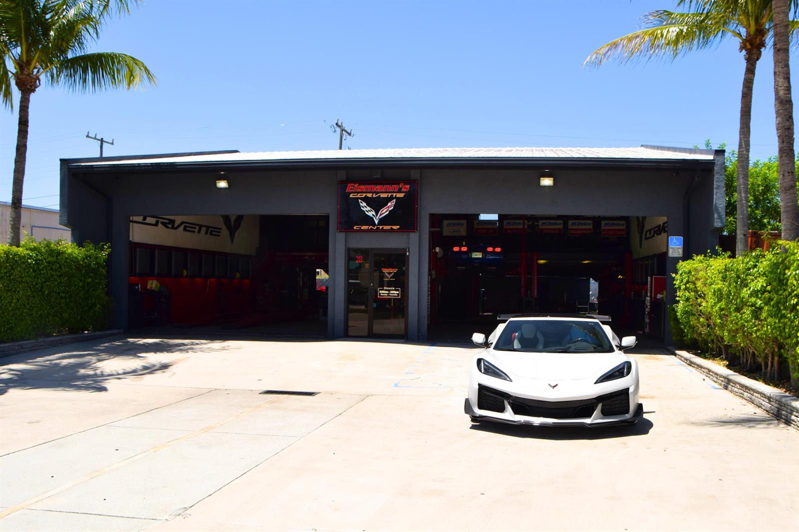 A white sports car is parked in front of a gray automotive repair shop building — 213 Venus Street, Jupiter FL 33458, JUPITER, FL