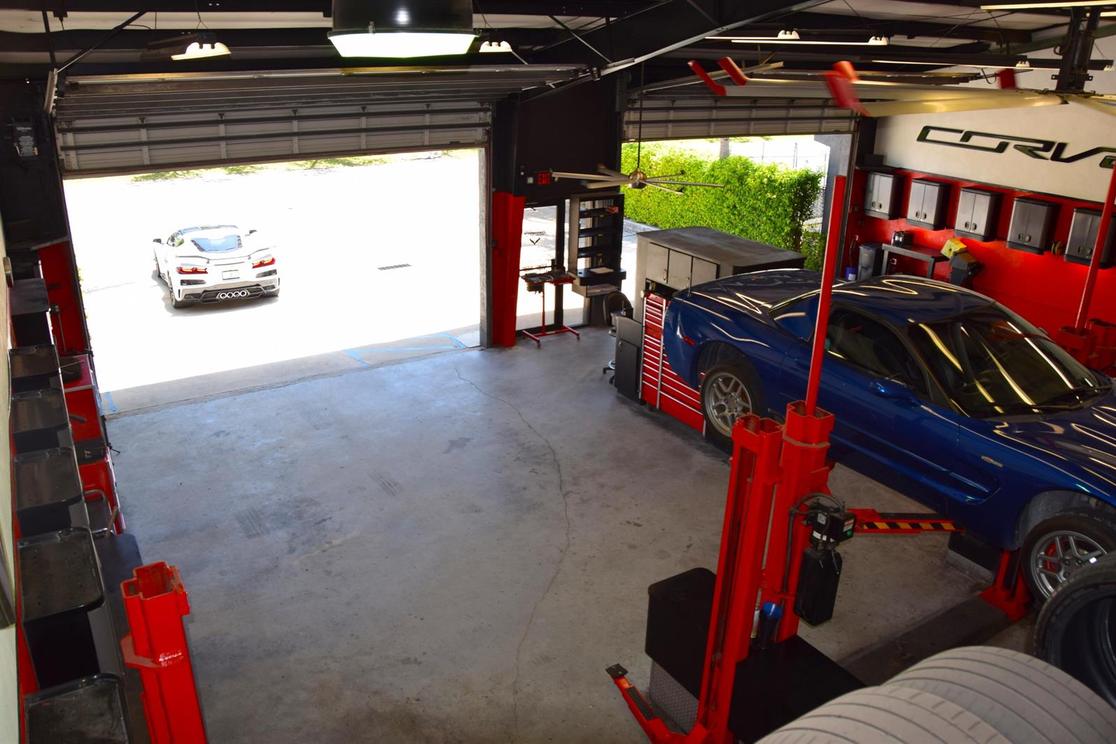 An elevated view of an automotive garage featuring a blue Corvette on a vehicle lift — 213 Venus Street, Jupiter FL 33458, JUPITER, FL