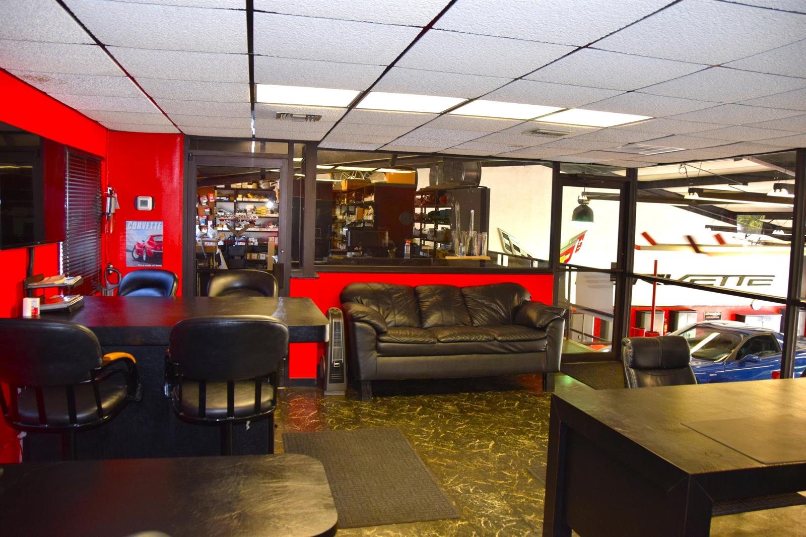 An office waiting area features a black leather sofa, dark desks, and red accent walls — 213 Venus Street, Jupiter FL 33458, JUPITER, FL