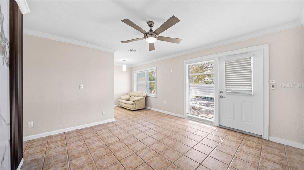A room with tiled flooring, a ceiling fan, a white door, and a small sofa — 170 POINSETTIA CIRCLE NE, PORT CHARLOTTE, FL