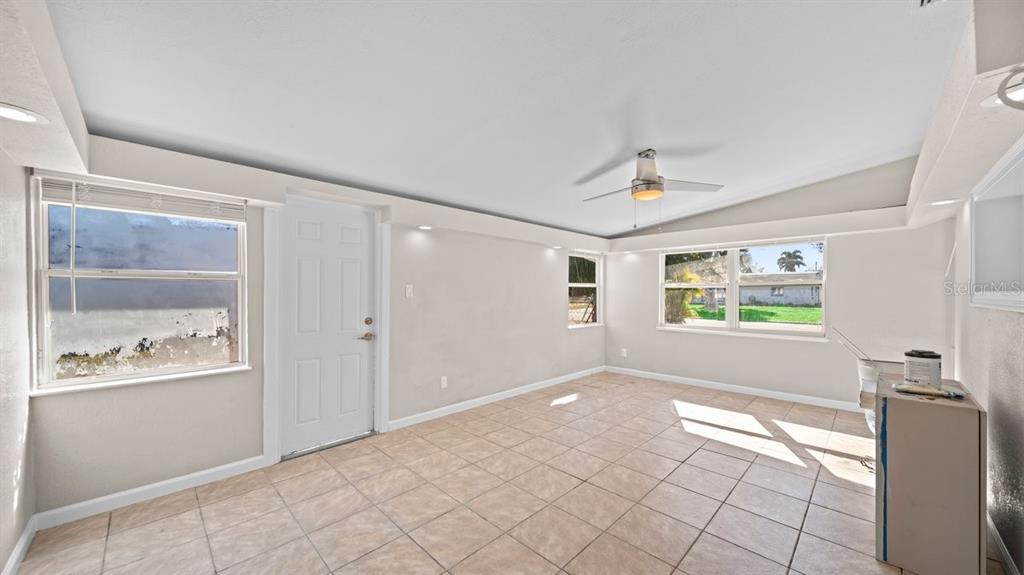 An empty room with light-colored tile flooring, a ceiling fan, and multiple windows — 170 POINSETTIA CIRCLE NE, PORT CHARLOTTE, FL