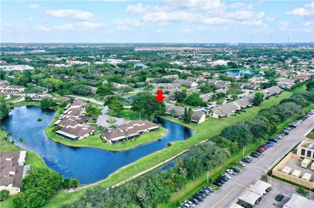 An aerial view shows residential buildings situated around a lake in a suburban neighborhood — 9364 Ketay Circle # 5, Boca Raton FL 33428, BOCA RATON, FL