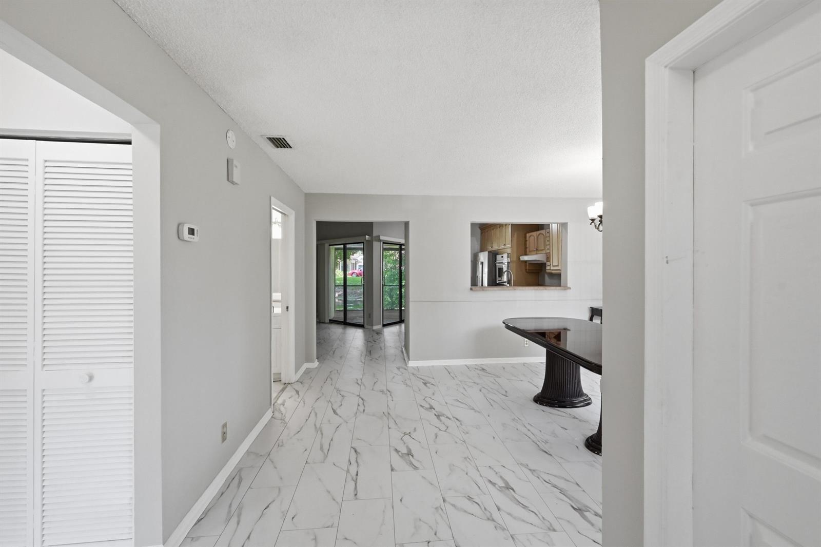 A dining area with marble-look tile flooring features a pass-through window to the kitchen — 9364 Ketay Circle # 5, Boca Raton FL 33428, BOCA RATON, FL