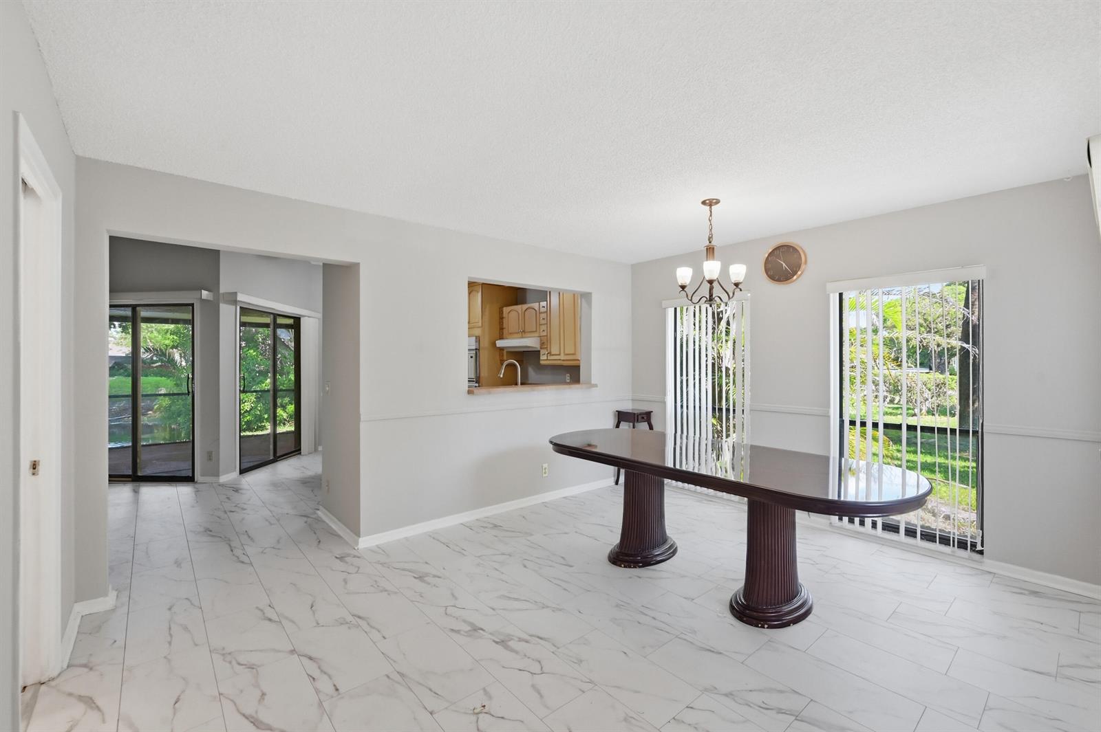 A dining room with a large dark table, marble-look tile floors, and sliding glass doors — 9364 Ketay Circle # 5, Boca Raton FL 33428, BOCA RATON, FL