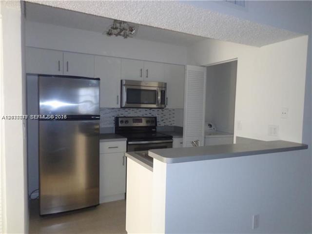 A kitchen features stainless steel appliances, white cabinetry, and a breakfast bar — 1267 SW 46th Ave # 2315, Pompano Beach FL 33069, POMPANO BEACH, FL