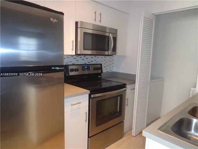 A kitchen features stainless steel appliances, white cabinets, and a tiled backsplash — 1267 SW 46th Ave # 2315, Pompano Beach FL 33069, POMPANO BEACH, FL