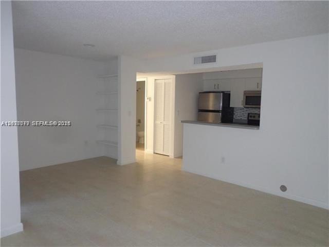 An open-concept living area features light tile flooring, built-in wall shelves, and a kitchen pass-through — 1267 SW 46th Ave # 2315, Pompano Beach FL 33069, POMPANO BEACH, FL