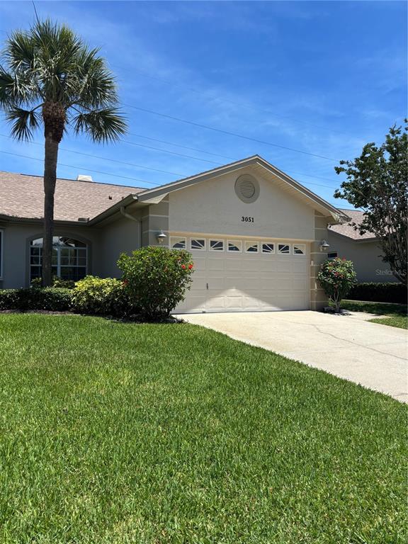 A single-story house with a beige exterior, a two-car garage, and a palm tree — 3051 BROOKFIELD LANE, CLEARWATER, FL
