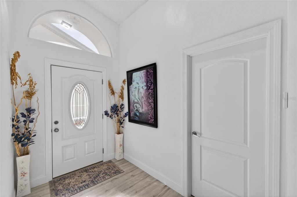 An entryway features a white front door with an oval window, light flooring, and decor — 3051 BROOKFIELD LANE, CLEARWATER, FL