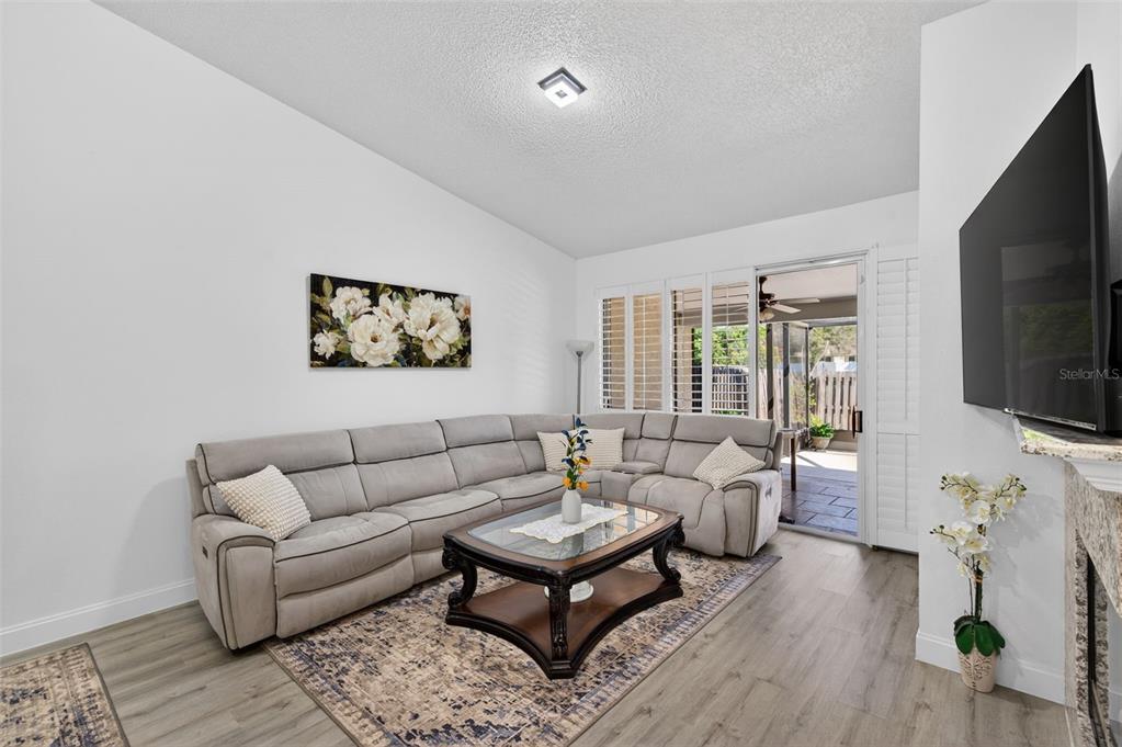 A living room features a gray sectional sofa, a glass-top coffee table, and sliding glass doors — 3051 BROOKFIELD LANE, CLEARWATER, FL
