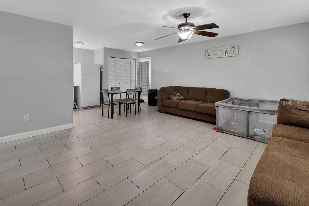 A living room with light tile flooring, a brown sofa, and an adjacent dining area — 2222 6TH AVENUE, DELAND, FL