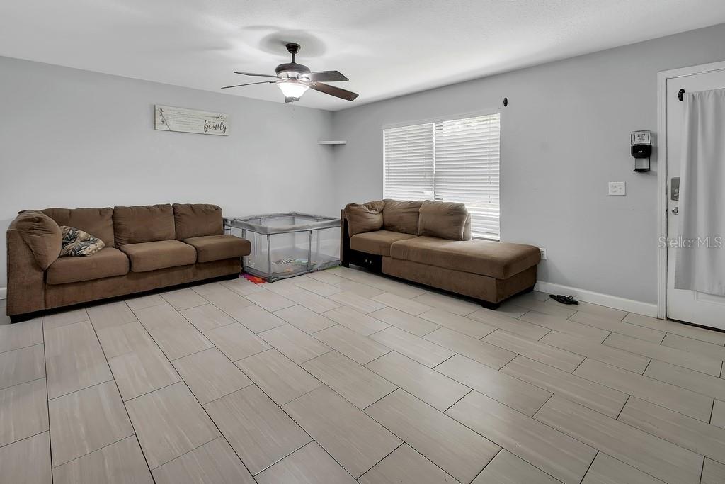 A living room features light gray walls, tile flooring, two brown sofas, and a playpen — 2222 6TH AVENUE, DELAND, FL